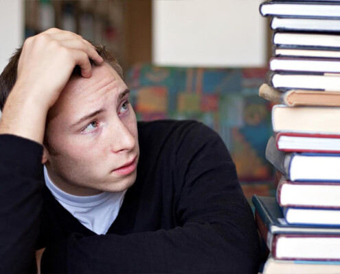 "A college student holds their hand against their head as they stare at the tower of textbooks next to them. Substance abuse treatment in New York, NY can help you overcome procrastination due to drug use. Learn more about outpatient substance abuse treatment in New York, NY by contacting a substance abuse psychiatrist in New York, NY. 10022