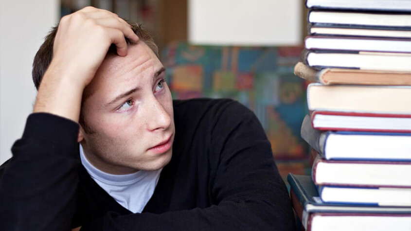 "A college student holds their hand against their head as they stare at the tower of textbooks next to them. Substance abuse treatment in New York, NY can help you overcome procrastination due to drug use. Learn more about outpatient substance abuse treatment in New York, NY by contacting a substance abuse psychiatrist in New York, NY. 10022