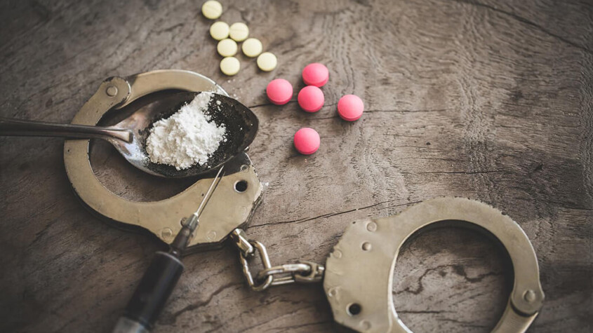 A close up of cuffs, pills, a syringe, and a powder in a spoon. A psychiatrist in New York, NY can offer treatment for opioid withdrawal in New York, NY. Learn how we can offer online opioid treatment in New York, NY and other services today.