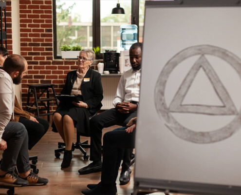 A group of people sit in a circle for an AA meeting. Learn more about how alcohol treatment in New York, NY can offer support by contacting a psychiatrist in New York, NY today. We offer alcohol addiction treatment in New York, NY and more.