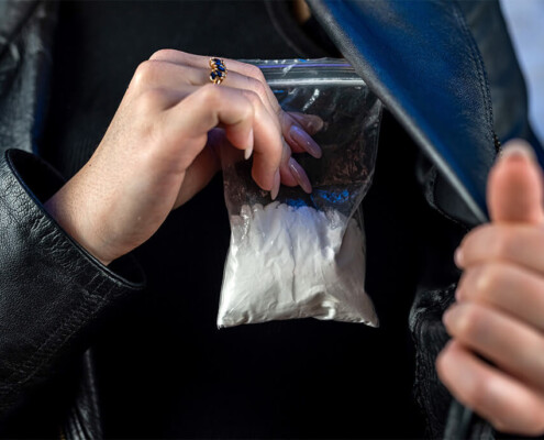 woman removing bag of cocaine from inner coat pocket