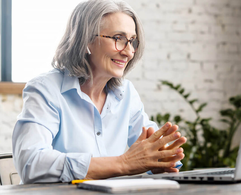 woman sits in front of laptop chatting on a video conference