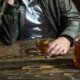 close up of man in a bar with glass and bottle of alcohol