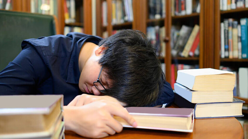 A college students sleeps with their head down while surrounded by books. Learn more about the support a drug addiction therapist in New York, NY can offer by searching for prescription drug addiction treatment in New York, NY today. A psychiatrist in New York, NY can offer support today.