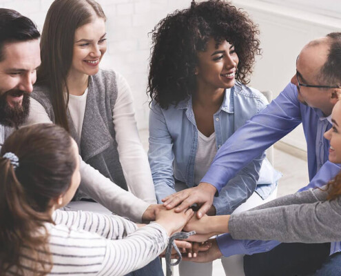 A group of people smile at one another while holding their hands in a pile. Learn how an addiction psychiatrist in New York, NY can help offer support for loved ones of those affected by addiction in New York, NY. Search for "addiction specialist nyc" for alcohol addiction help in New York, NY today.