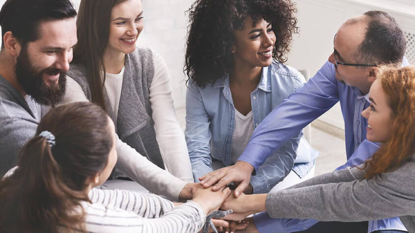 A group of people smile at one another while holding their hands in a pile. Learn how an addiction psychiatrist in New York, NY can help offer support for loved ones of those affected by addiction in New York, NY. Search for "addiction specialist nyc" for alcohol addiction help in New York, NY today.