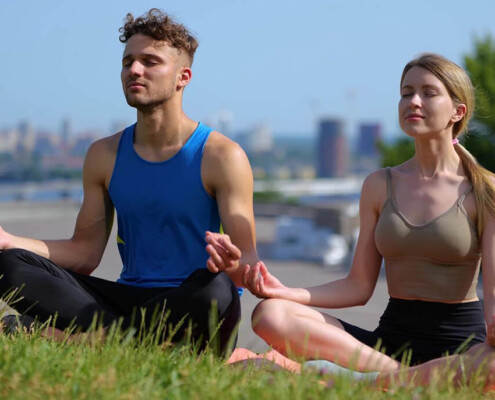 A couple smiles while practicing yoga. Learn how an adult psychiatrist in New York, NY can offer support with addiction treatment in New York, NY and other services today. Contact an online psychiatrist in New York, NY to learn more.