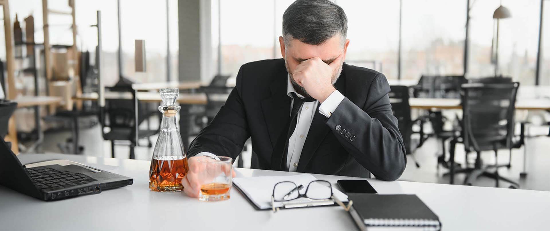 Stressed executive drinking at office. This could represent someone with an alcohol addiction. Get alcohol addiction treatment in New York City with an addiction treatment psychologist at Addiction Treatment Expert 10022
