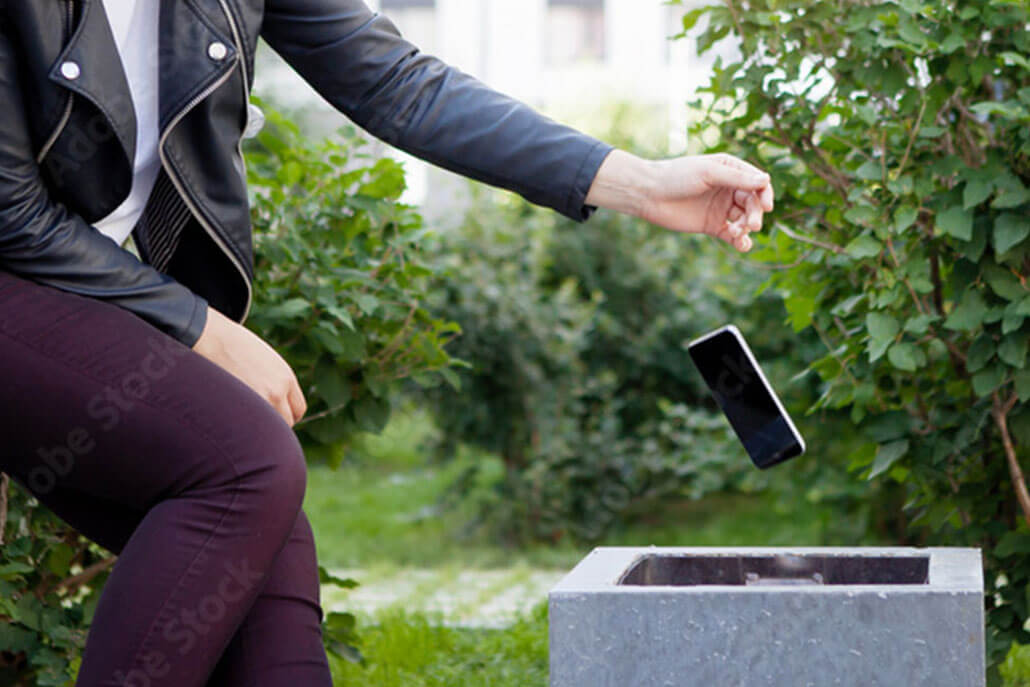 Woman tossing a mobile phone in trashcan