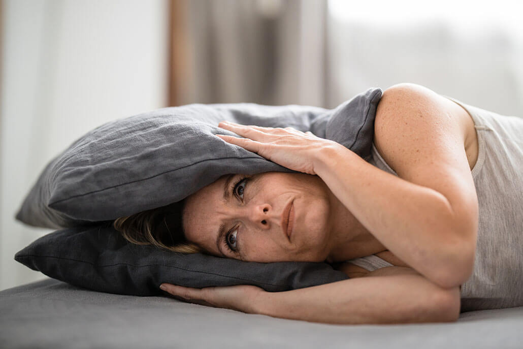 A woman holds both sides of her head. Her ears are covered by pillows. Dual diagnosis treatment in New York, NY can help you overcome addiction and psychiatric disorders. Contact a dual diagnosis therapist in New York, NY to learn more about co occurring treatment in NYC, Manhattan and other dual diagnosis treatment centers in New York, NY. 10022