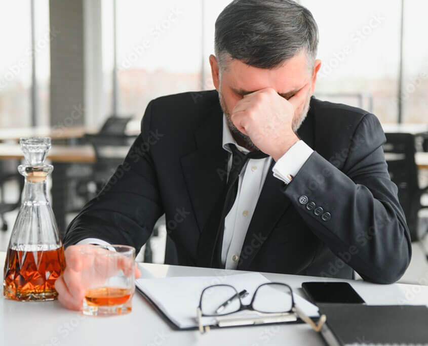 Stressed executive drinking at office. This could represent someone with an alcohol addiction. Get alcohol addiction treatment in New York City with an addiction treatment psychologist at Addiction Treatment Expert 10022