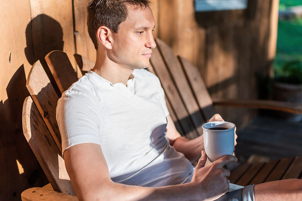 Man sits peacefully in rocking chair on his outside deck