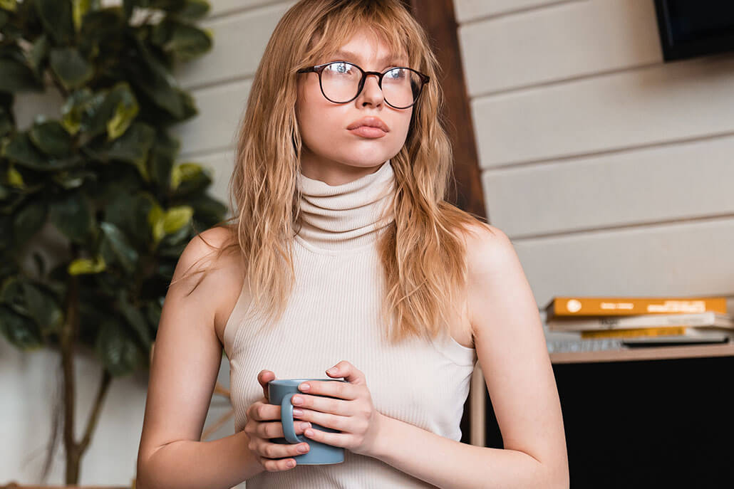 Young woman sitting on floor holding a cup of coffee. Young adult psychiatry in New York, NY can offer support for those in times of transition. Contact a psychiatrist for young adults in New York, NY to learn more about our services! 10022