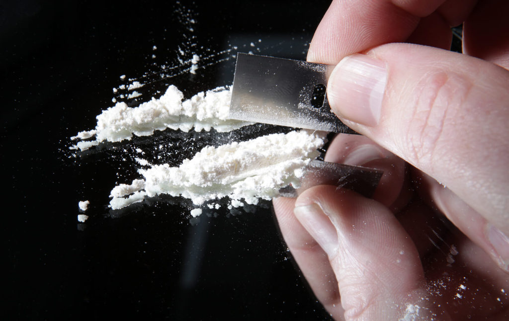 A close up of a person with a razor cutting white powder. Cocaine treatment in New York, NY can offer support in overcoming symptoms. Learn more about treatment for cocaine addiction in New York, NY by contacting a psychiatrist in New York, NY.