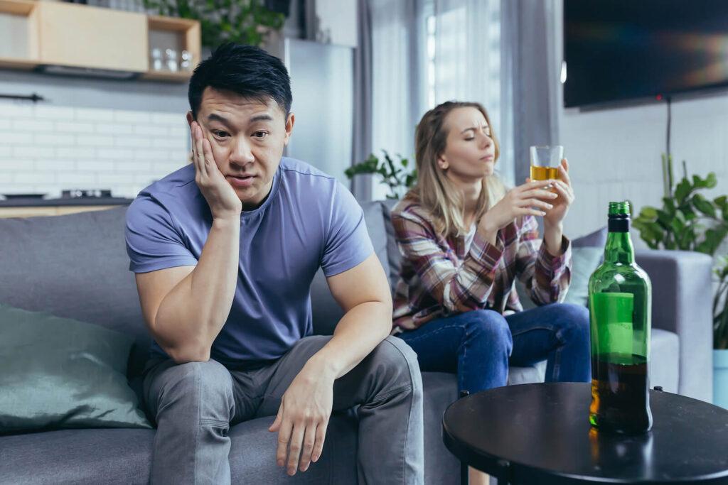 A man sits with a concerned expression next to his partner holding alcohol. Alcohol addiction treatment in New York, NY can offer alcohol addiction help in New York, NY and across the state. Learn more about how alcohol treatment in New York, NY can offer support today.