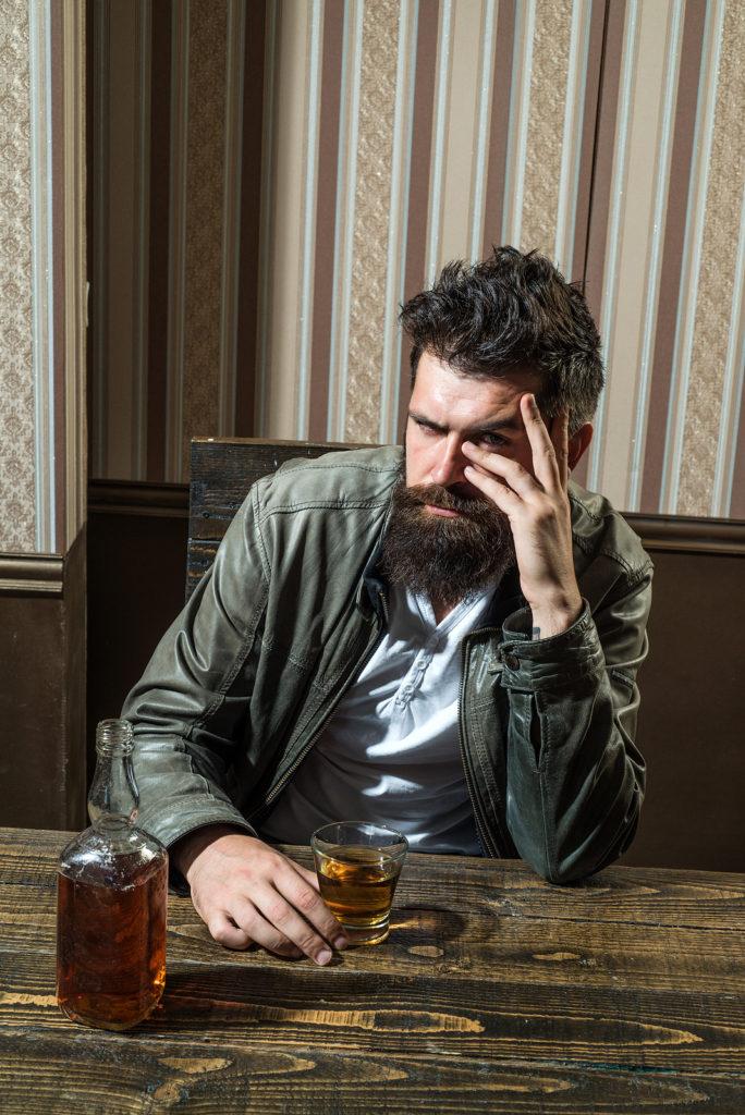 A man looks at the camera with an agitated look while drinking liquor. Alcohol addiction treatment in New York, NY can offer support for families of alcoholics in New York, NY. Learn more about alcohol addiction help in New York, NY today.