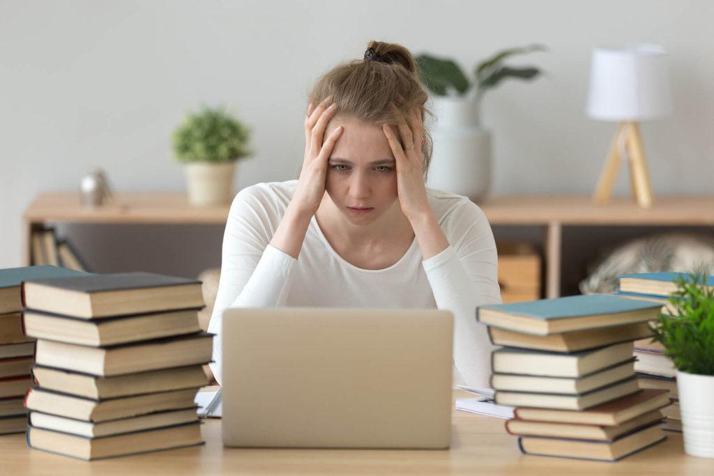 A college student surrounded by books holds her head in her hands while looking at her laptop. This could represent the stress caused by drug use that substance abuse treatment in New York, NY can address. Feel free to learn more about how a substance abuse psychiatrist in New York, NY can help. Visit with Stephen Gilman, the Addiction Treatment Expert in NYC, Manhattan. 10022