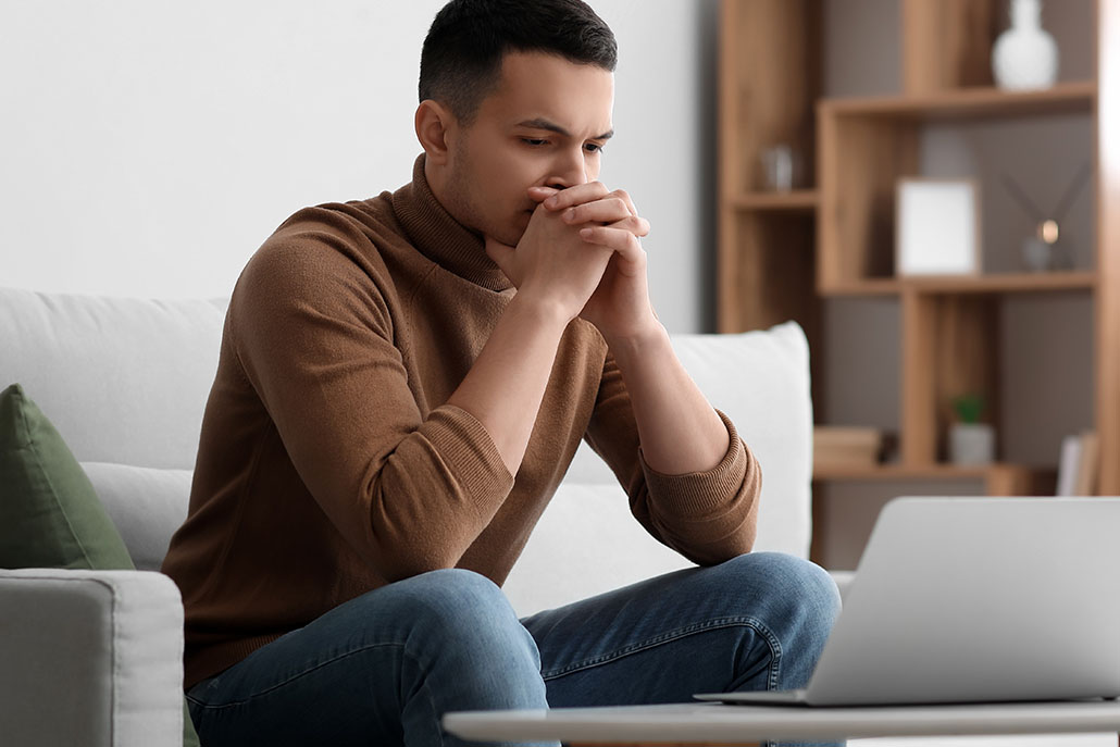 Worried man stares and laptop screen