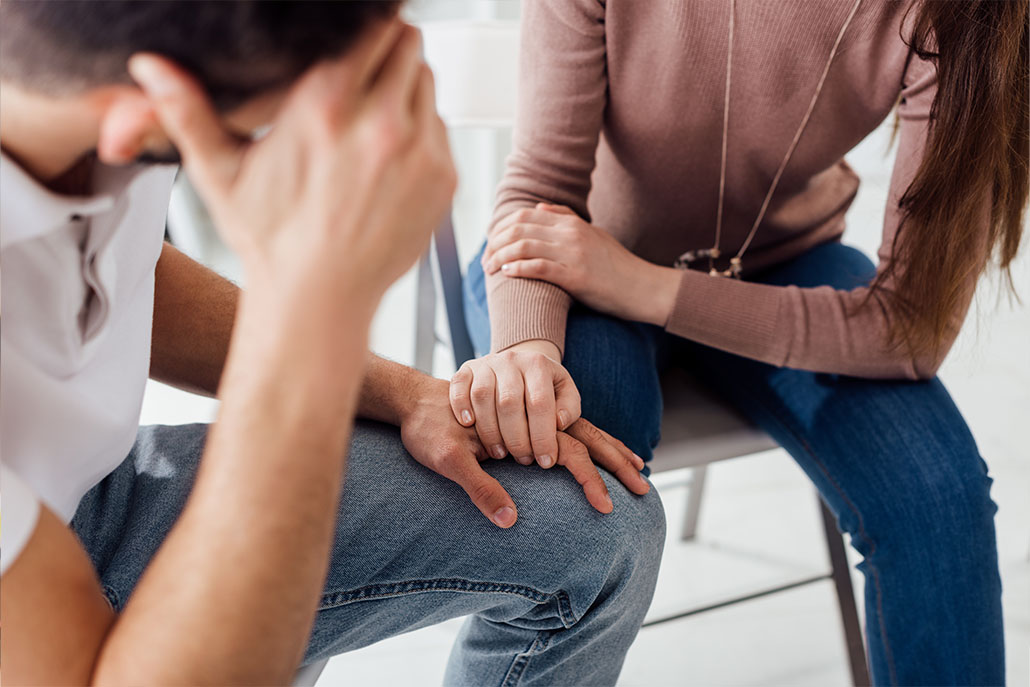 Woman comforts man in group addiction therapy session